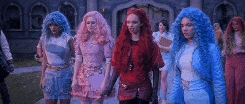 a group of girls are standing in front of a building wearing wigs .