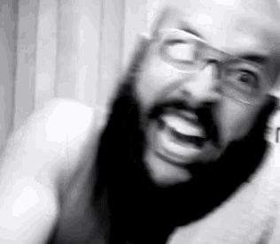 a man with a beard and glasses is making a funny face .