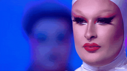 a close up of a drag queen 's face with a blue background and a watermark that says ' xtreme '