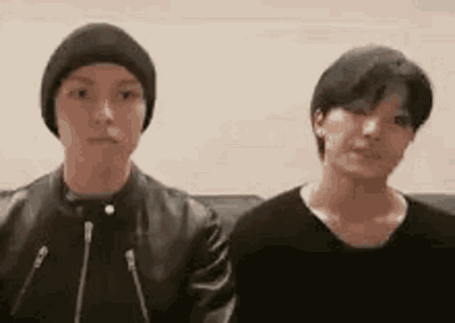 two young men are standing next to each other looking at the camera .