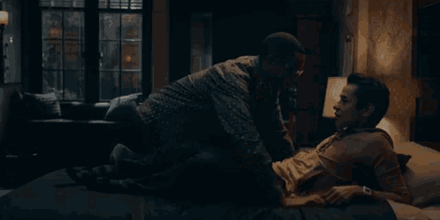 two men are laying on a bed and having sex .