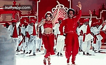 a man and a woman are dancing in front of a crowd of people in red costume .