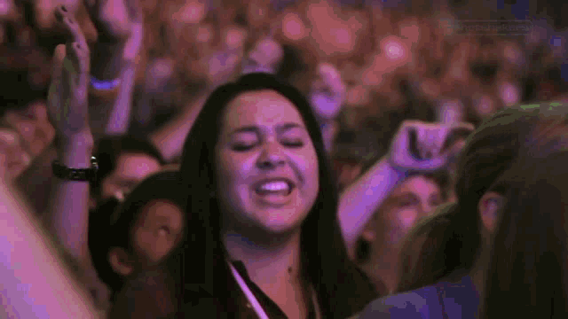 a woman with her eyes closed is in a crowd of people