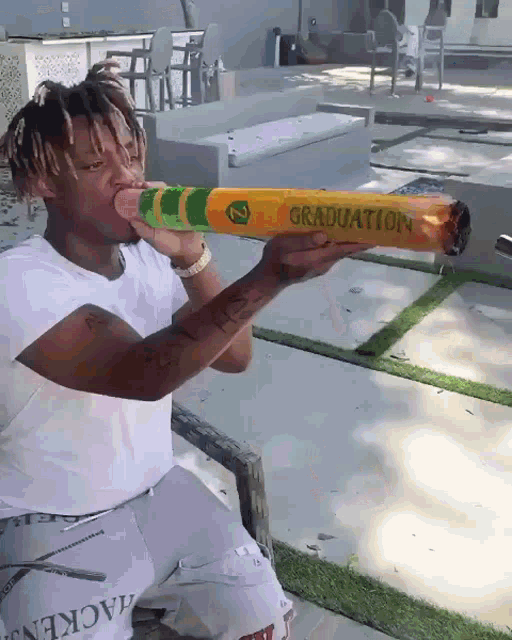 a man in a white shirt is holding a crayon that says graduation