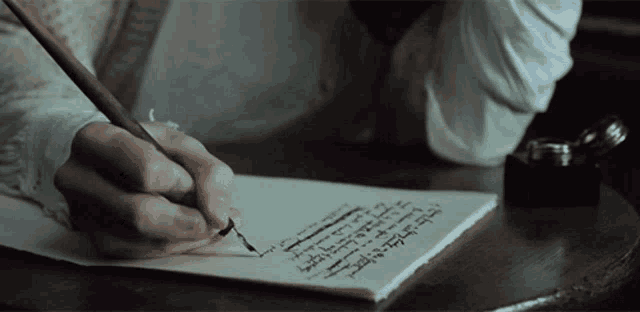 a person is writing on a piece of paper with arabic writing on it