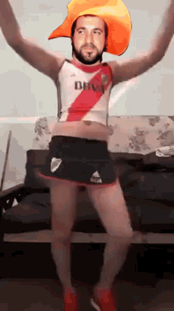 a man wearing a cowboy hat and shorts is dancing in front of a couch