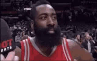 a basketball player with a beard is wearing a red jersey and talking into a microphone .