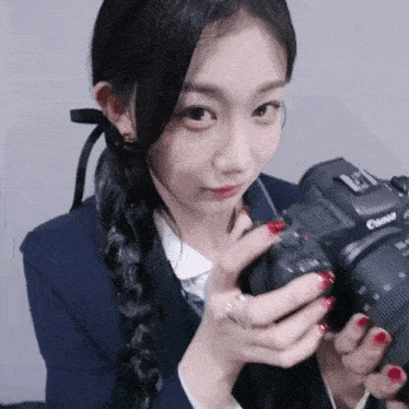 a young woman holding a canon camera in her hands