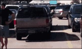 a man is walking in a parking lot with a 4gifs.com logo on the bottom right