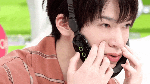 a young man wearing headphones is talking on a cellphone