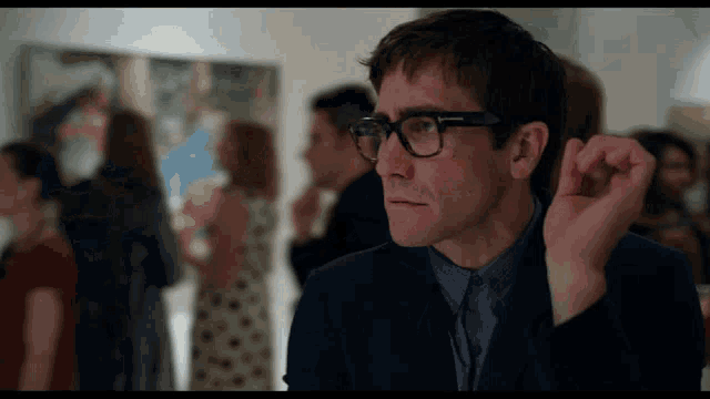 a man wearing glasses and a suit is looking at something