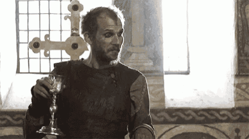 a man is holding a glass of wine in his hand in a room .
