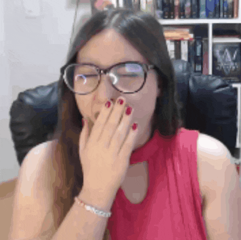 the woman is wearing glasses and covering her mouth with her hand