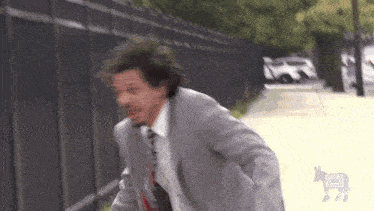a man in a suit and tie is running down a sidewalk ..