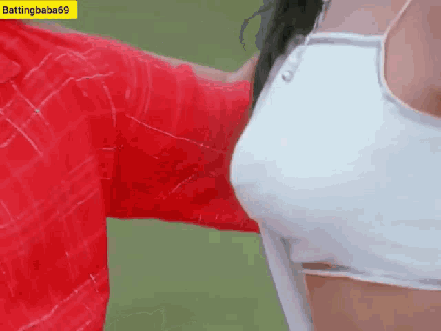 a man in a red shirt is touching a woman 's breast while wearing a white bra .