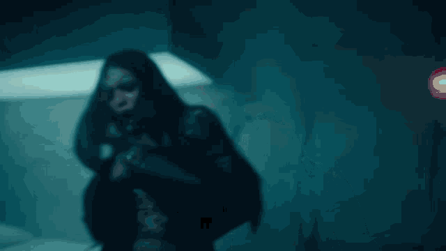 a woman with long hair is standing in a dark room with a coca cola shirt on