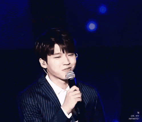 a man in a suit is holding a microphone and smiling while standing on a stage .