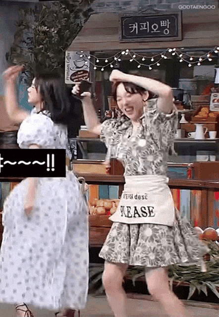 two women are dancing in front of a sign that says " tease "