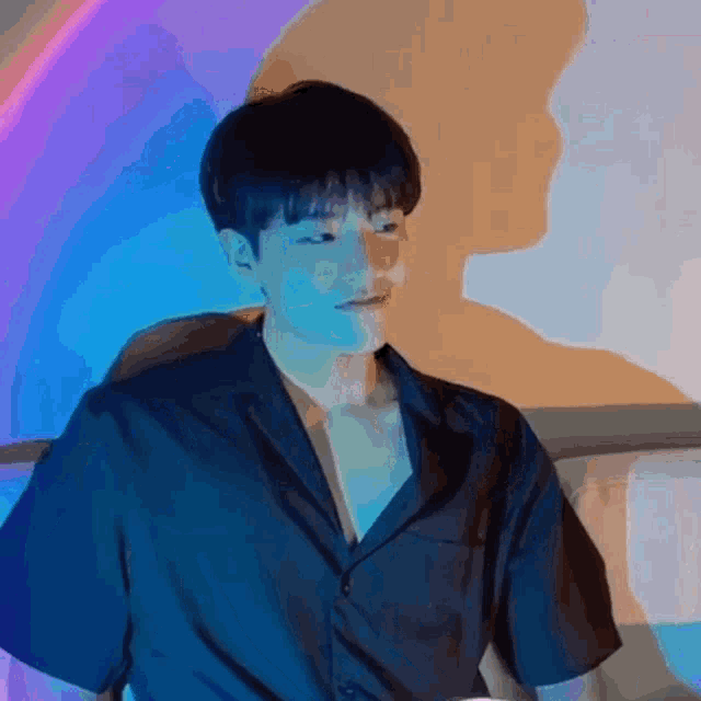 a man in a black shirt is standing in front of a rainbow light