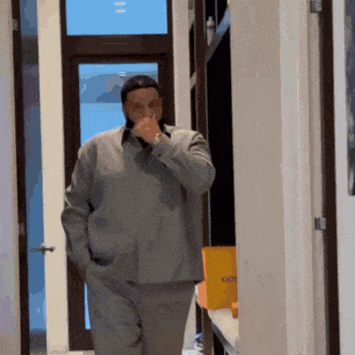 a man standing in a hallway with his hands in his pockets and a yellow box that says kioo on it