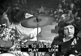a black and white photo of a man playing drums in a band .