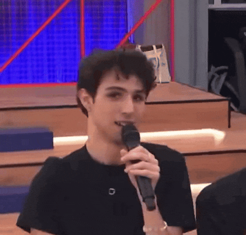 a young man is holding a microphone in his mouth and talking into it .