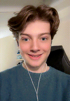 a young man wearing headphones and a blue shirt is smiling for the camera .