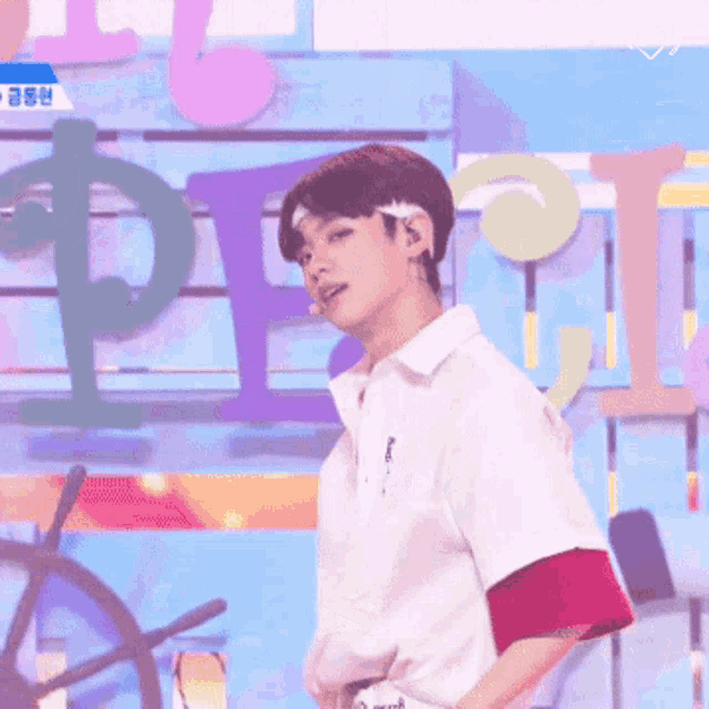 a man wearing a headband and a white shirt stands in front of a wall with letters p and i