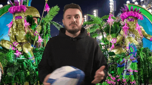 a man in a black hoodie is holding a blue and white ball in front of a parade