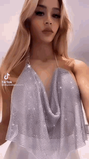 a woman is wearing a silver top with rhinestones on it and a plunging neckline .