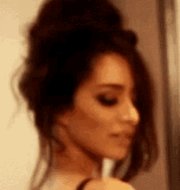 a close up of a woman 's face with a bun on her head .