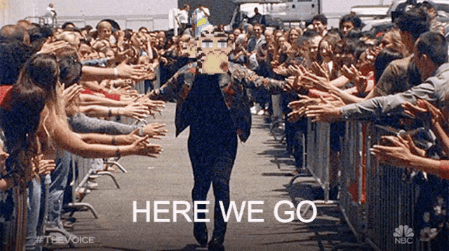 a man is walking through a crowd of people with the words here we go written on the bottom .