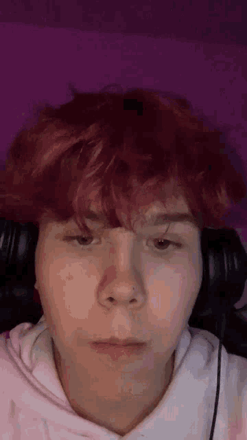 a close up of a person 's face with red hair and headphones on .