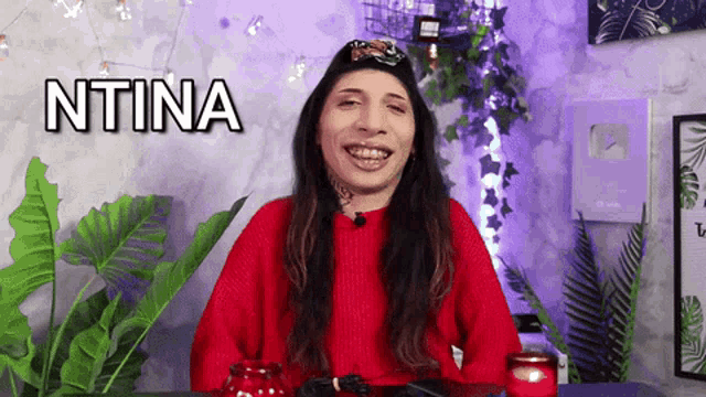 a woman wearing a red sweater and a black hat with the word ntina above her head