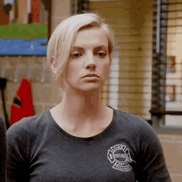 a woman wearing a chicago fire department t-shirt is looking at the camera .