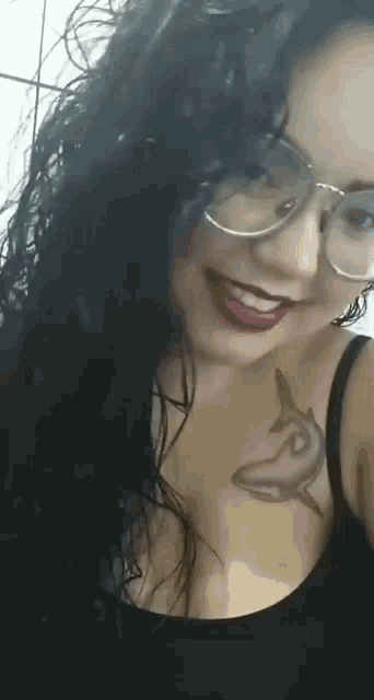 a woman with glasses and a tattoo of a dolphin on her chest smiles .