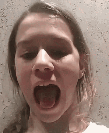 a young girl is making a funny face with her tongue hanging out .