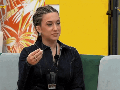 a woman is sitting on a green couch and holding something in her hand .