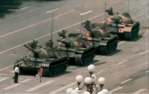 a row of military tanks are parked on a city street