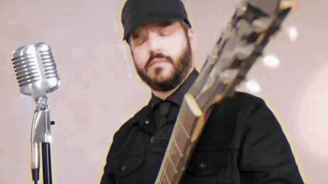 a man with a beard is holding a guitar and singing into a microphone .