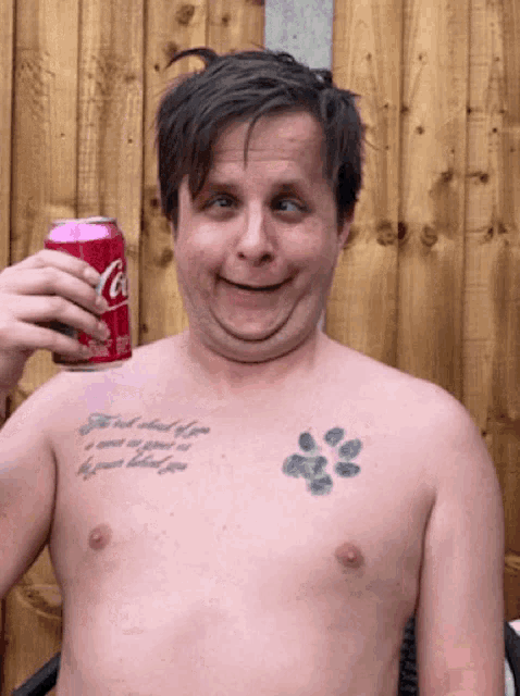 a shirtless man is holding a can of coca cola