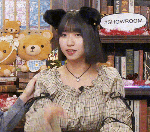 a woman wearing a cat ear headband stands in front of a sign that says showroom