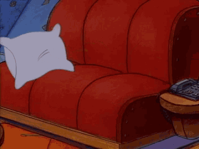 a cartoon character is laying on a couch with a pillow and a telephone .