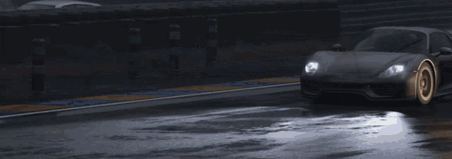 a gray sports car is driving down a wet road at night