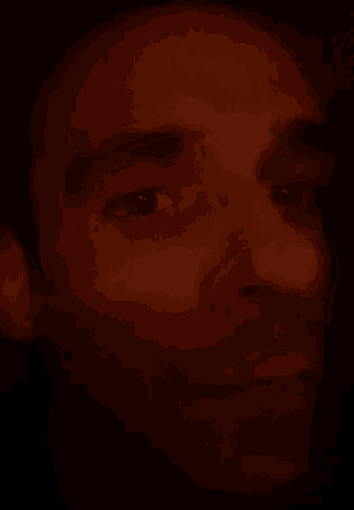 a close up of a man 's face in the dark with a blurred background .