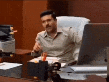 a man is sitting at a desk with a computer .