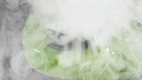 smoke is coming out of a green object on a black surface