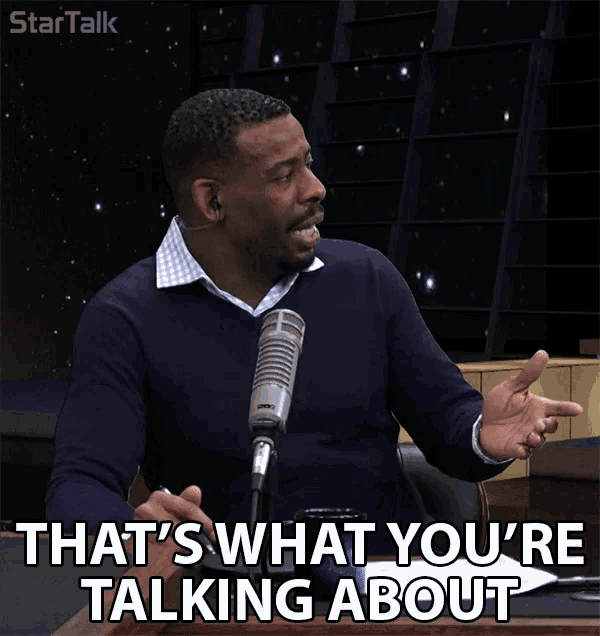 a man sitting in front of a microphone with the words that 's what you 're talking about below him