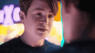 a close up of two young men looking at each other in a dark room .