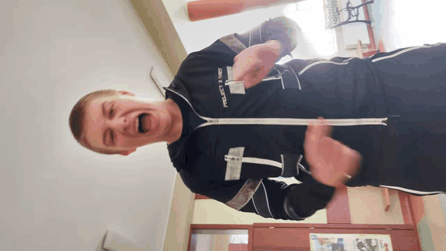 a man wearing a black jacket with the letter i on it
